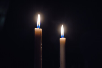 Two burning candles on a dark background symbolizing remembrance, mourning, hope and spirituality. Minimalistic low light scene with soft glow and deep shadows.