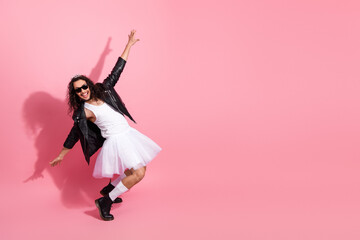 Happy nonbinary lgbt dancer wears tutu and leather jacket on pink background, celebrating individuality