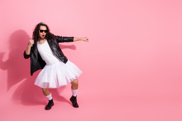 Male dancer in leather jacket and ballerina dress strikes a dynamic pose on a pink backdrop, celebrating LGBT diversity