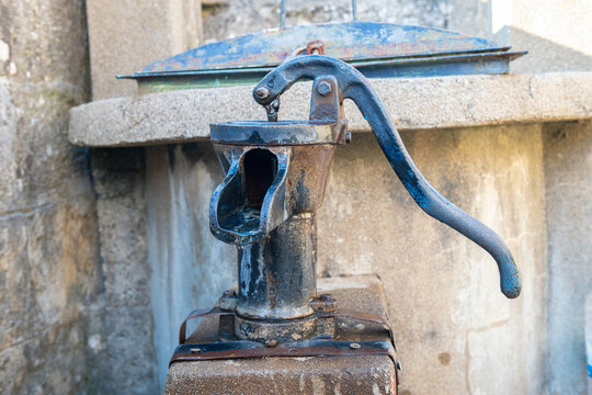 The rusty and nostalgic manual water pump standing in the corner of the garden is an old and aesthetic detail of rural life.