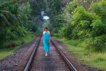 Woman Walking on Abandoned Train Tracks Through Lush Greenery