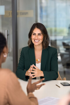 Happy confident Hispanic business professional woman talking to coworker, partner, laughing, discussing collaboration. Positive job candidate speaking to recruiter on interview. Vertical shot