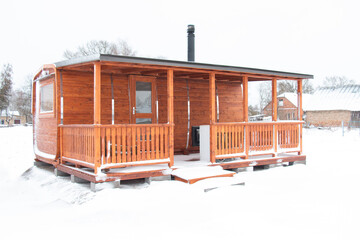 new house made of wood, eco house in nature on a winter day. snow-covered fluffy spruce trees, walks through the winter white forest.