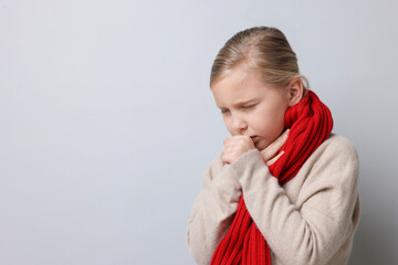 Little girl coughing on light background, space for text. Cold symptom