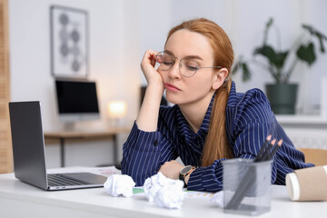 Obraz premium Sleepy woman with laptop at workplace in office