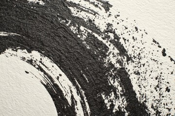 Close-up of textured black ink swish against white paper, creating a semi-circular brushstroke effect
