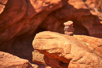 Cairn on Sandstone Ledge with Sunlit Red Rocks in Desert Valley