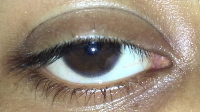 Extreme macro close up of Indian woman eye blinking with natural reflection and eyelashes detail. Concept of human vision, emotion, attention, observation, beauty, and healthcare. 