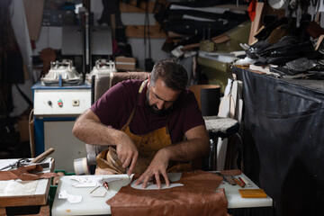 Leather artisan at work shaping leather pieces in a busy workshop studio during handmade production
