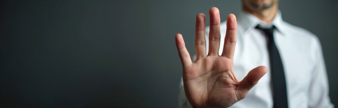 Man in white shirt and tie shows open palm. Gesture of stop or denial. Unidentified person, neutral background. Professional pose. Facing forward.