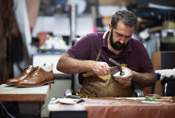 Skilled craftsman shaping a leather shoe in a busy workshop, focused on handcrafting and detail
