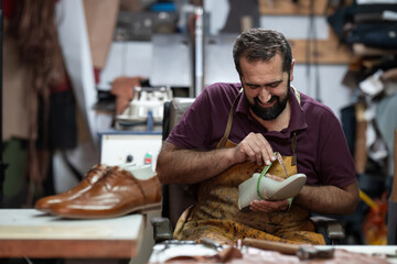 Cobbler at work, measuring a shoe in his leather workshop with a smile and focus on craftsmanship