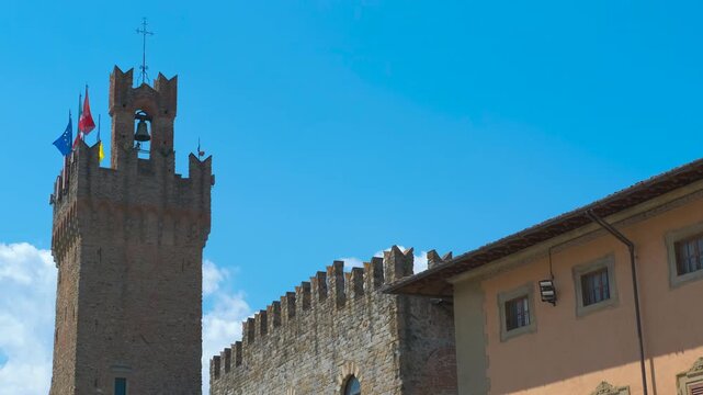 Palazzo pretorio tower and municipal palace in arezzo, italy. Wonderful zooming out view of the palazzo pretorio tower and municipal palace in arezzo, italy, with flags waving in the wind