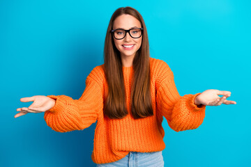 Young woman in orange knit sweater smiles with glasses against blue background for fashion lifestyle and shopping vibe