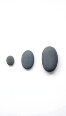 Minimal rock collection: three smooth river stones, varying sizes, matte gray, top-down, no shadow