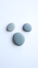 Minimal rock collection: three smooth river stones, varying sizes, matte gray, top-down, no shadow