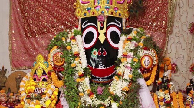 Lord Jagannath idol adorned with flowers and ornaments during religious ceremony. Indian spirituality and Hindu worship concept.