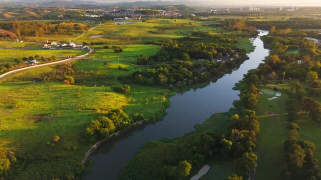 aerial view of a river crossing Sao Jose dos Campos city during sunrise with astonishing colors, very green grass and a blue/orange sky