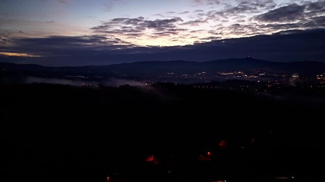 serene predawn panorama showcasing distant illumination fading amidst thick clouds and gentle