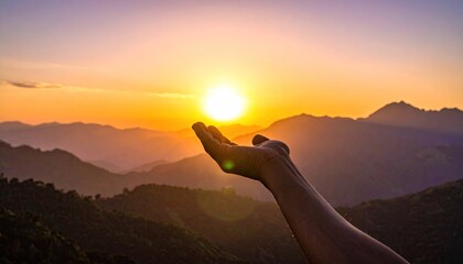 Hand Reaching Towards Bright Sun Setting Over Layered Mountain Ridges During Golden Hour With Hazy Atmosphere
