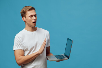 Man holding laptop in one hand and making a stop gesture with the other, surprised or worried...