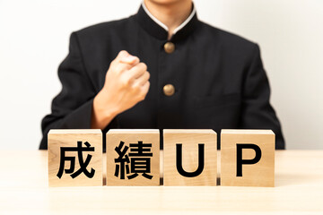 「成績UP」と書かれたブロックとガッツポーズをする男子学生