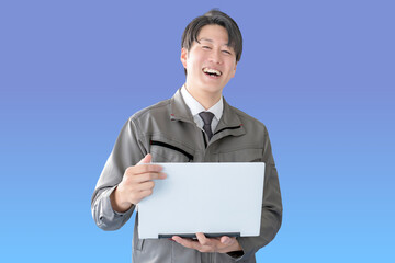 青背景と笑顔の作業服男性とPC