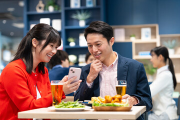 飲食店でスマホを見るミドルのカップル