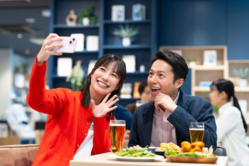 飲食店で写真を撮るミドルのカップル