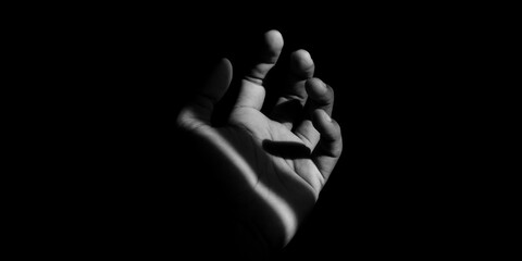 Fototapeta premium dramatic black and white of an open human palm reaching out from the darkness