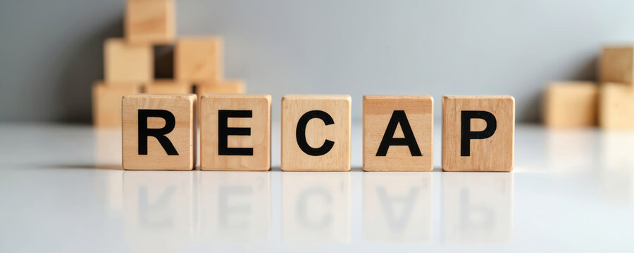 Wooden blocks spell out RECAP on reflective white surface against blurred gray background. Stacked blocks suggest organization or building process. Visualizes summarization for business or education.