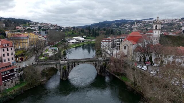 Historic St Goncalo stone bridge over Tamega River connecting Sao Goncalo catholic church area, Amarante city landscape, Aerial pullback shot