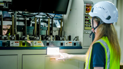 Two female robotics engineers in an R and D lab program an artificial intelligence system. One operates the HMI screen while the other holds a tablet with diagnostic data.