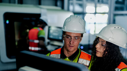 Engineers use a laptop to program an AI system for an industrial robot. The team is in a smart factory cleanroom, working on a high-tech microchip manufacturing line.