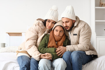 Frozen family with winter clothes and lack of heating hugging in bedroom