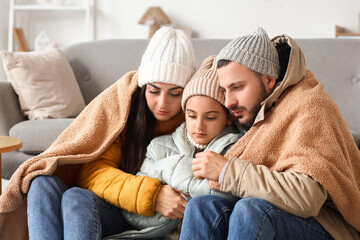 Frozen family in winter clothes with plaid and lack of heating at home