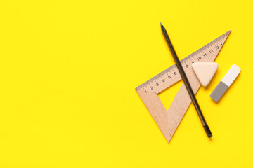 Triangle ruler with pencil and different rubber erasers on yellow background