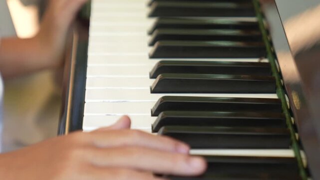 Small girls hands press piano keys in a playful untrained way, focusing on sound exploration rather than structured musical learning.