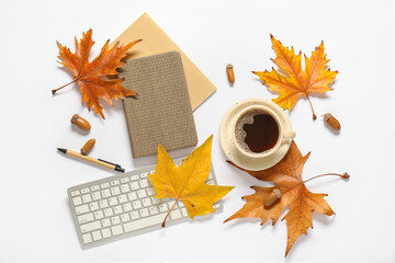 Cup of coffee with computer keyboard, notebooks, autumn leaves and acorns on white background
