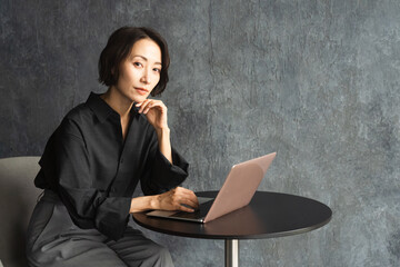 テーブルでラップトップを操作する女性　ライフスタイルイメージ