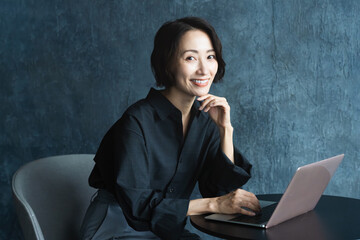 テーブルでラップトップを操作する女性　ライフスタイルイメージ