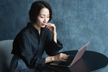 テーブルでラップトップを操作する女性　ライフスタイルイメージ