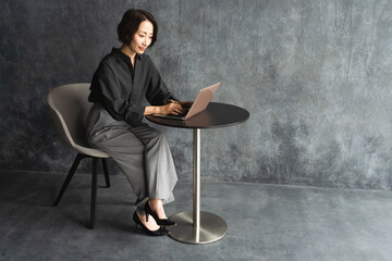 テーブルでラップトップを操作する女性　ライフスタイルイメージ