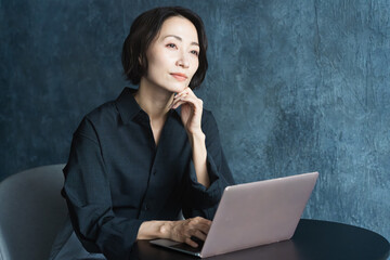 テーブルでラップトップを操作する女性　ライフスタイルイメージ