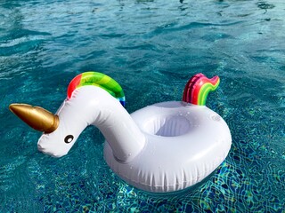 white unicorn inflatable balloon floating on blue swimming pool water