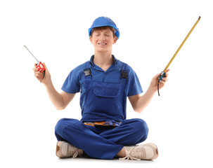 Young male construction worker with measuring tapes sitting on white background