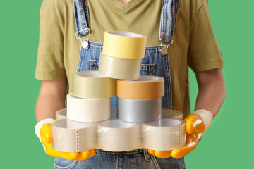 Young woman with adhesive tape rolls on green background, closeup