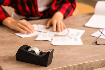 Young woman taping torn document on table, closeup