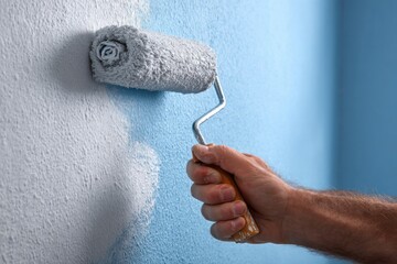 Close-up of hand painting wall with roller