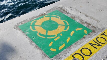 Warning sign on dock near water in sunny weather